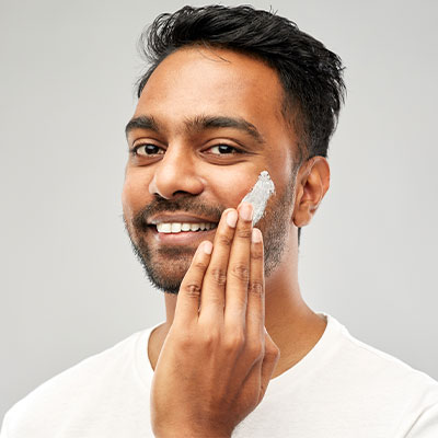 Man applying Pevonia's Soothing Sensitive Skin Cream to his cheek.