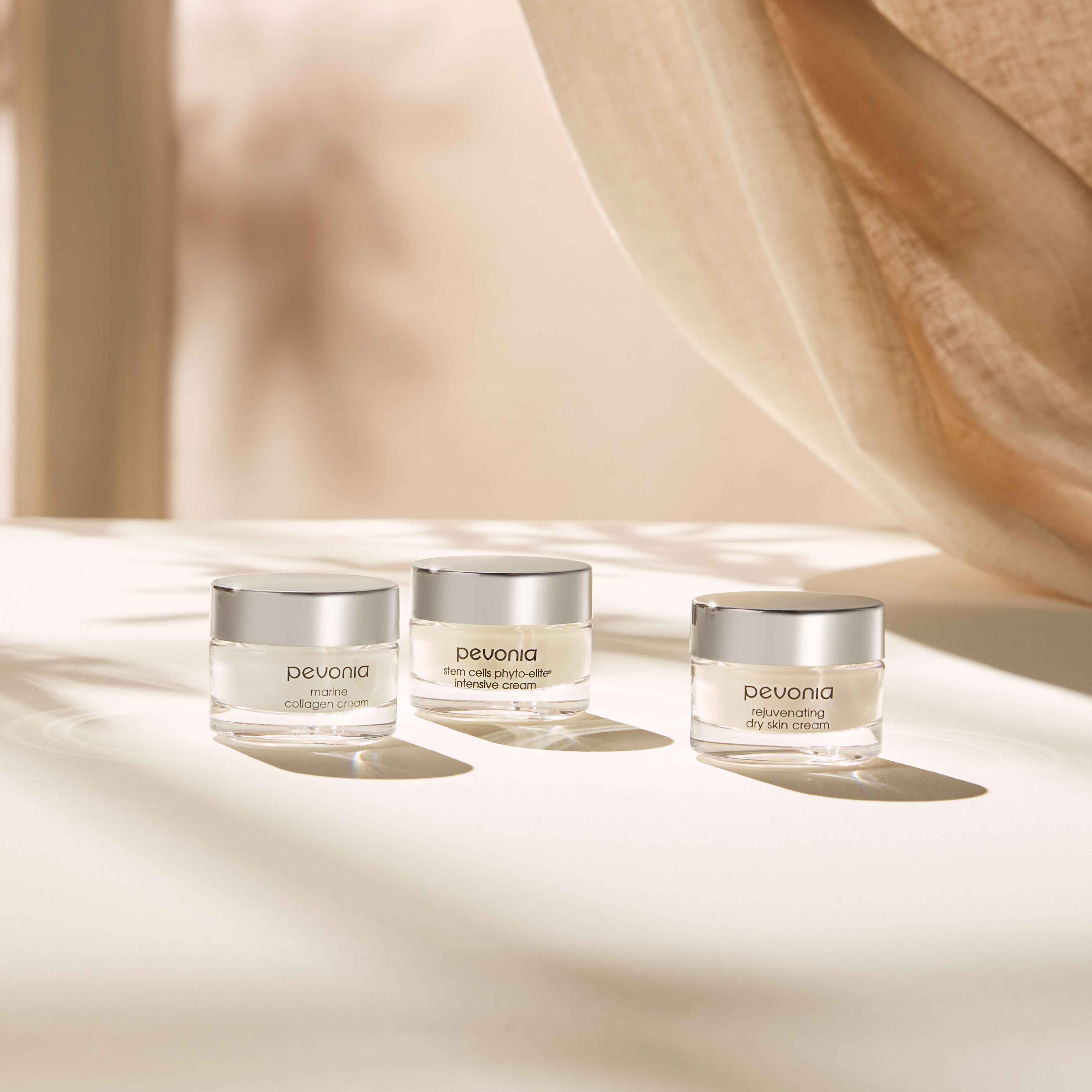 Three Pevonia trial-size creams sitting next to one another, basking in the sunlight from a nearby window.
