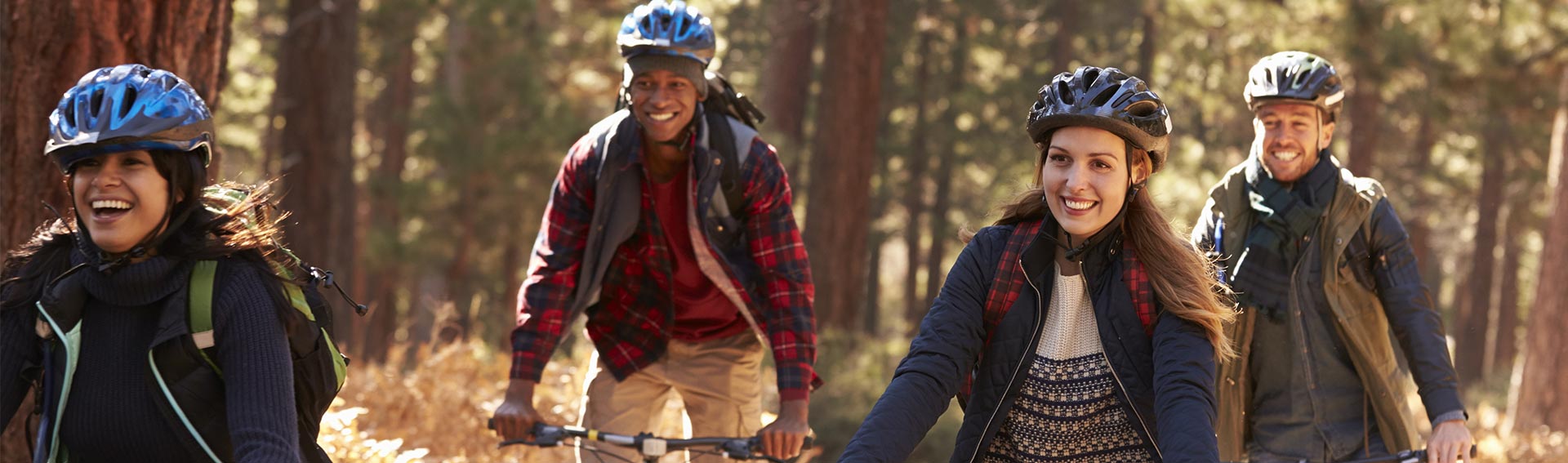A group of friends biking through the woods during the Fall.
