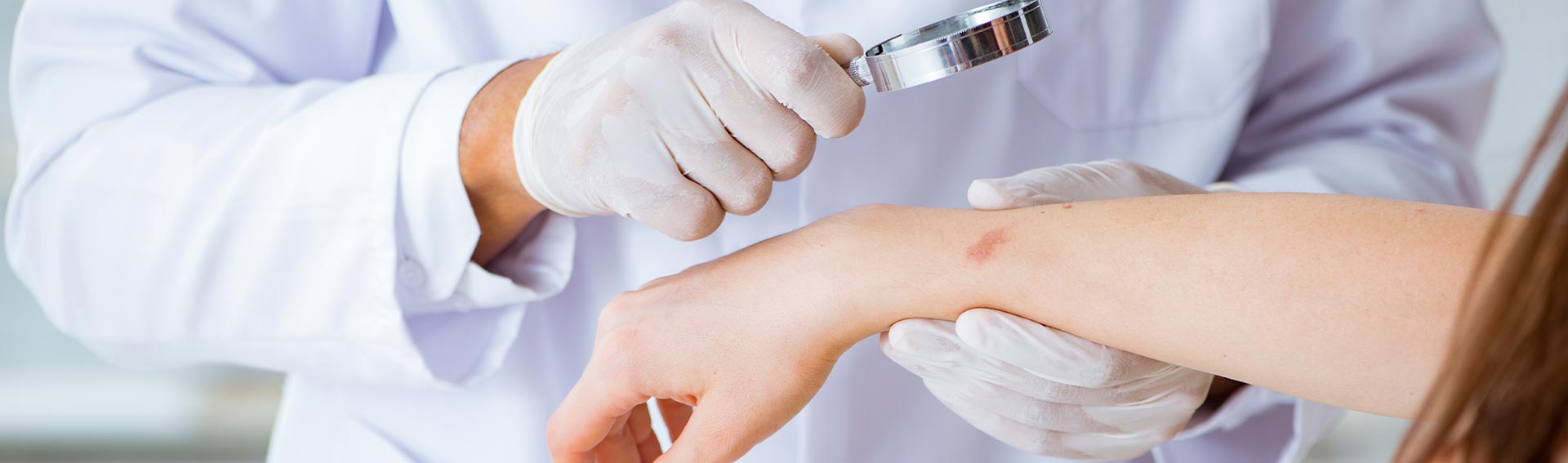 A doctor using a magnifying glass to inspect a woman's skin.
