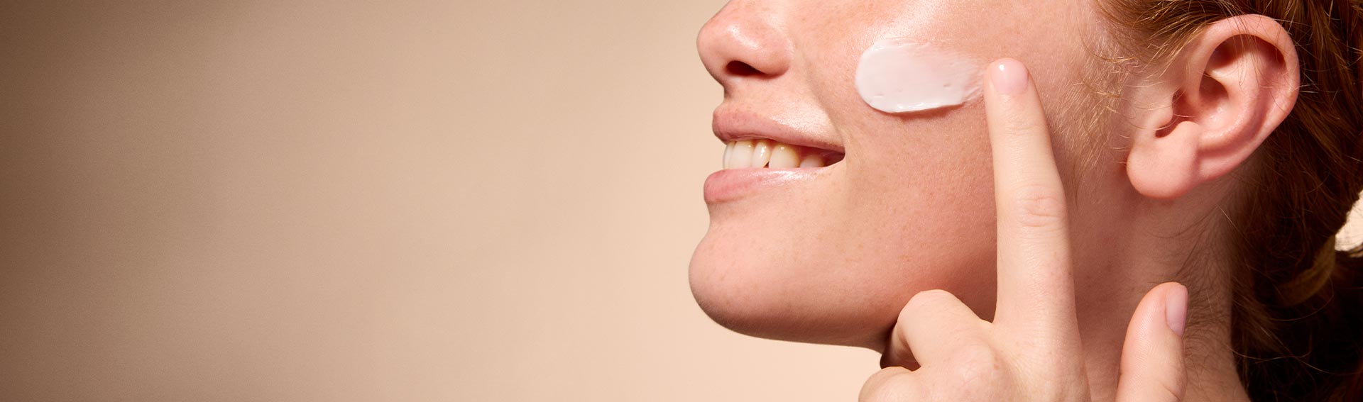 A woman applying Pevonia's Marine Collagen Cream to her cheek.